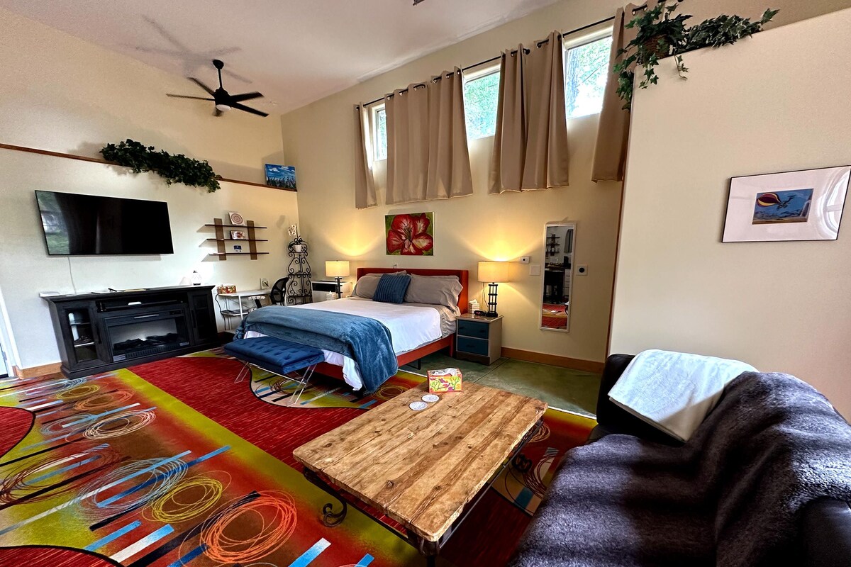 A hotel room with a bed, a desk, a television, and a sofa.