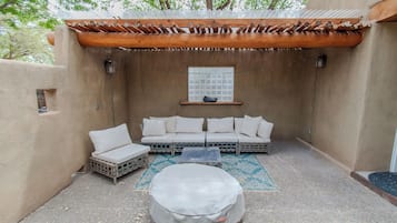 A covered outdoor seating area with a wooden pergola, a sofa set, and a round table.