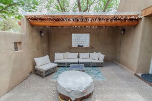 A covered outdoor seating area with a wooden pergola, a sofa set, and a round table. - Santuario Grande (Los Ranchos de Albuquerque)