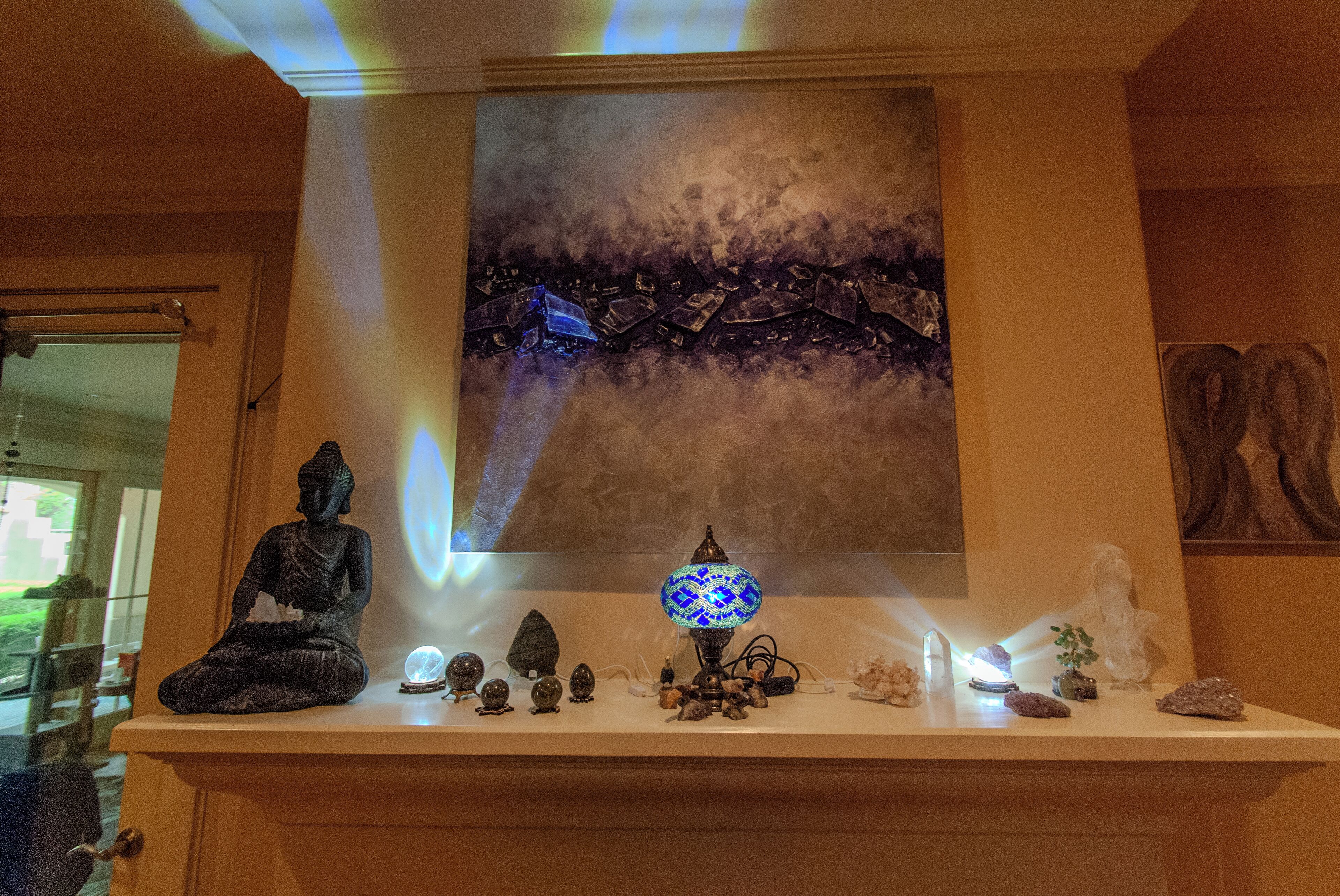 Ein Zimmer mit Buddha-Statue, einem Gemälde und verschiedenen Dekorationen auf einem Regal.
