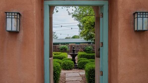 An arched entrance with a teal door leading to a pathway surrounded by greenery.