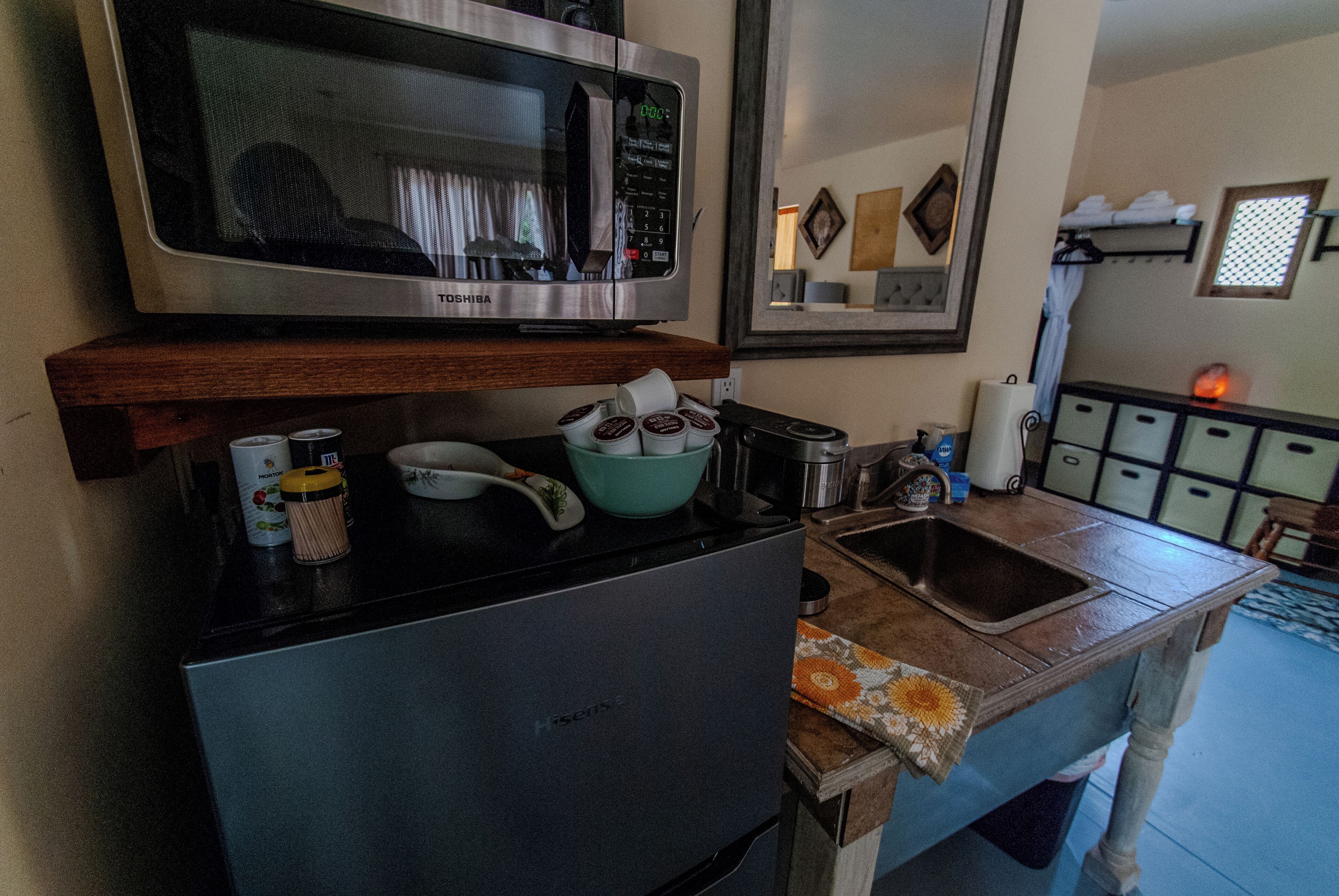Una cocina compacta equipada con microondas, estufa, fregadero y diversos utensilios de cocina.