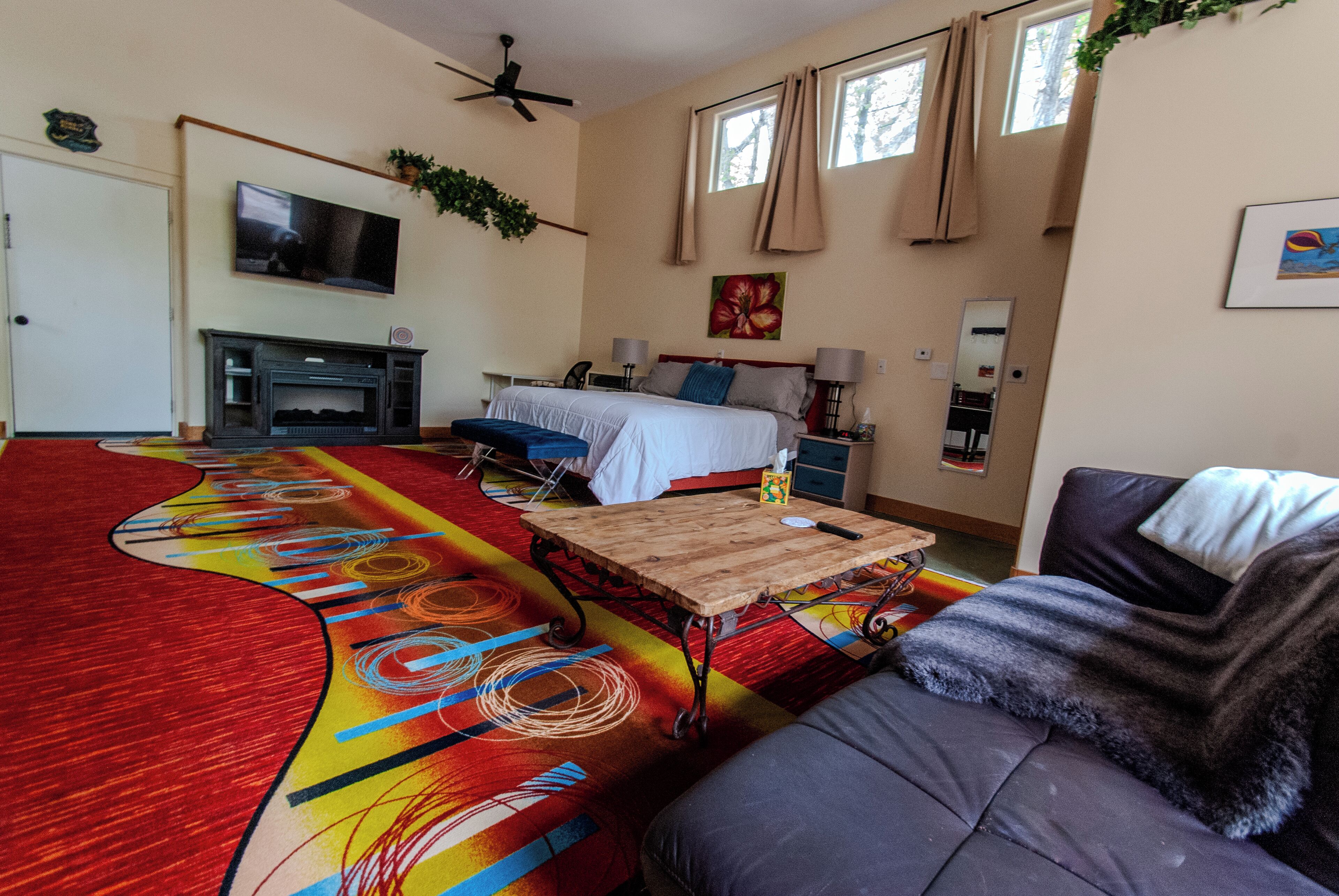 A bedroom with a bed, bedside tables, a TV, and a window with curtains.