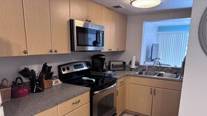 A kitchen with wooden cabinets, a microwave, a stove, a toaster, and a sink. - Great 2 BR Condo, 7 minutes to Siesta Key (Sarasota)
