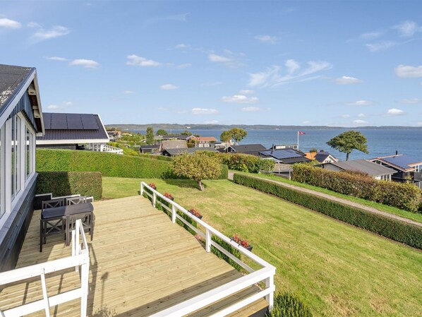 A residential area with a wooden deck, a view of the sea, and houses with solar panels.
