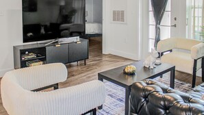 A modern living room with a flat-screen TV, a sofa, a chair, and a coffee table.