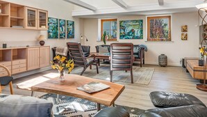 A spacious living room with high ceilings, wooden furniture, and artwork on the walls.