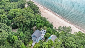 Vista aérea de una propiedad costera con playa, abundante vegetación y dos casas.