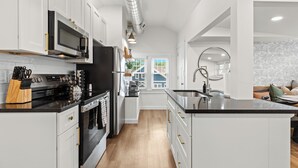 A modern kitchen with white cabinetry, a black countertop, and stainless steel appliances.