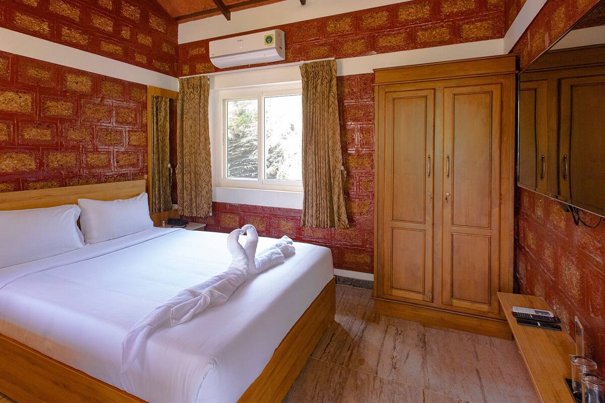 Une chambre d’hôtel avec un lit en bois, une armoire et une fenêtre avec des rideaux.