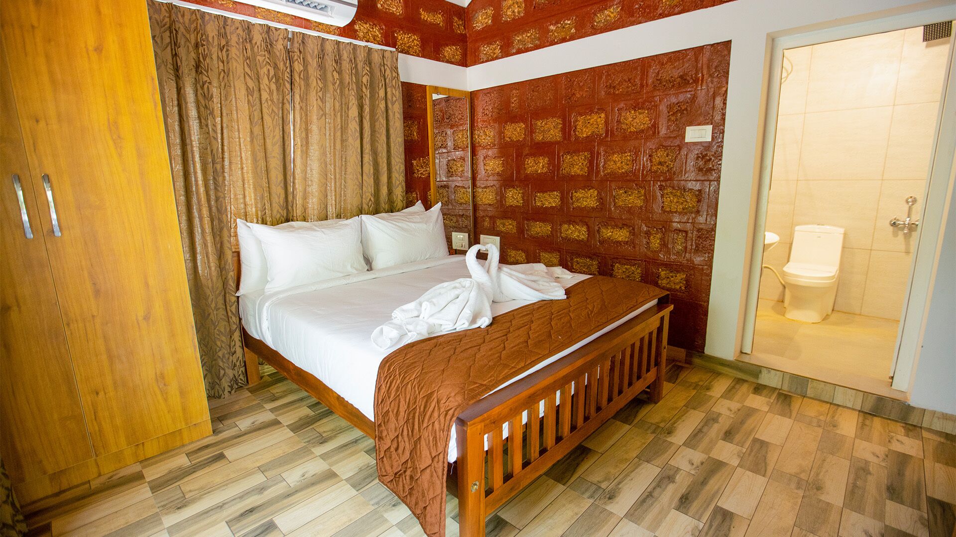 Habitación de hotel con una cama de madera, un armario, un baño con inodoro y una pared con diseño.