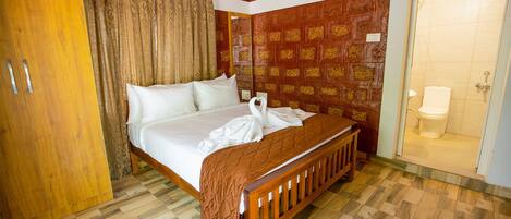 Habitación de hotel con una cama de madera, un armario, un baño con inodoro y una pared con diseño.