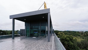 A modern building with a glass facade and a covered terrace. - One Budget Hotel Chiangrai Baanmai (Chiang Rai)