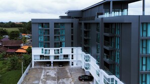 A modern multi-story building with a rooftop parking area and a white balcony. - One Budget Hotel Chiangrai Baanmai (Chiang Rai)
