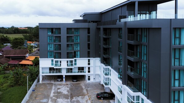 Ein modernes, mehrgeschossiges Gebäude mit einer Parkebene auf dem Dach und einem weißen Balkon.