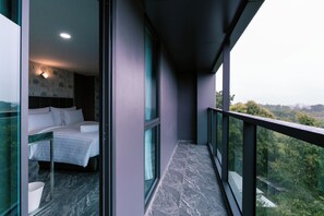 A modern hotel room with a balcony, a bed, and a view of the surrounding landscape. - One Budget Hotel Chiangrai Baanmai (Chiang Rai)