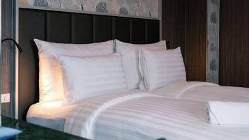 Una cama bien hecha con sábanas blancas y un cabecero con estampado floral.