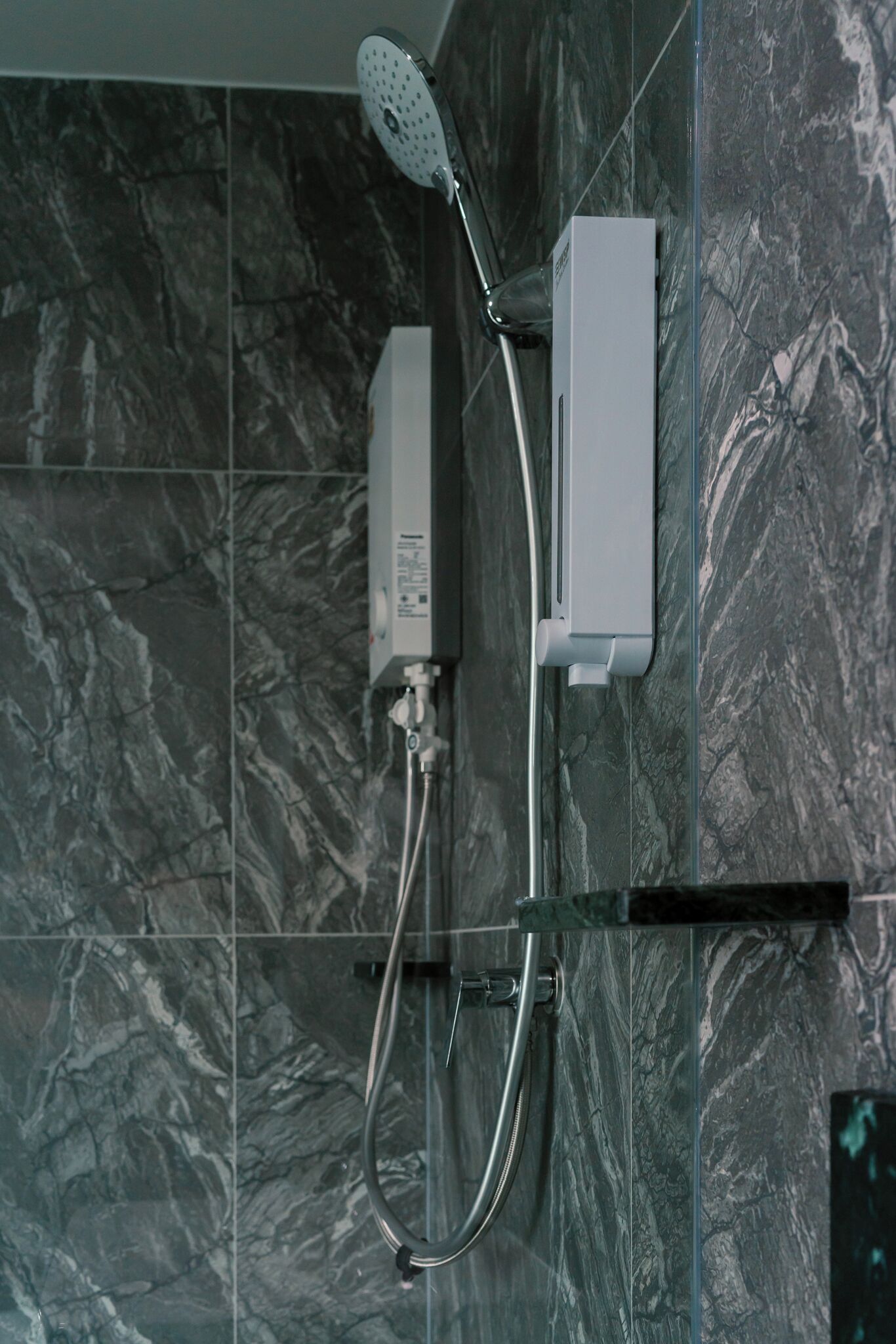 A modern shower with a handheld showerhead and a wall-mounted control panel.