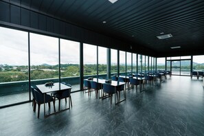 A modern dining area with large windows, multiple tables, and chairs. - One Budget Hotel Chiangrai Baanmai (Chiang Rai)