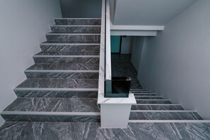 A staircase with dark marble steps and white handrails, leading to a landing with a glass door. - One Budget Hotel Chiangrai Baanmai (Chiang Rai)