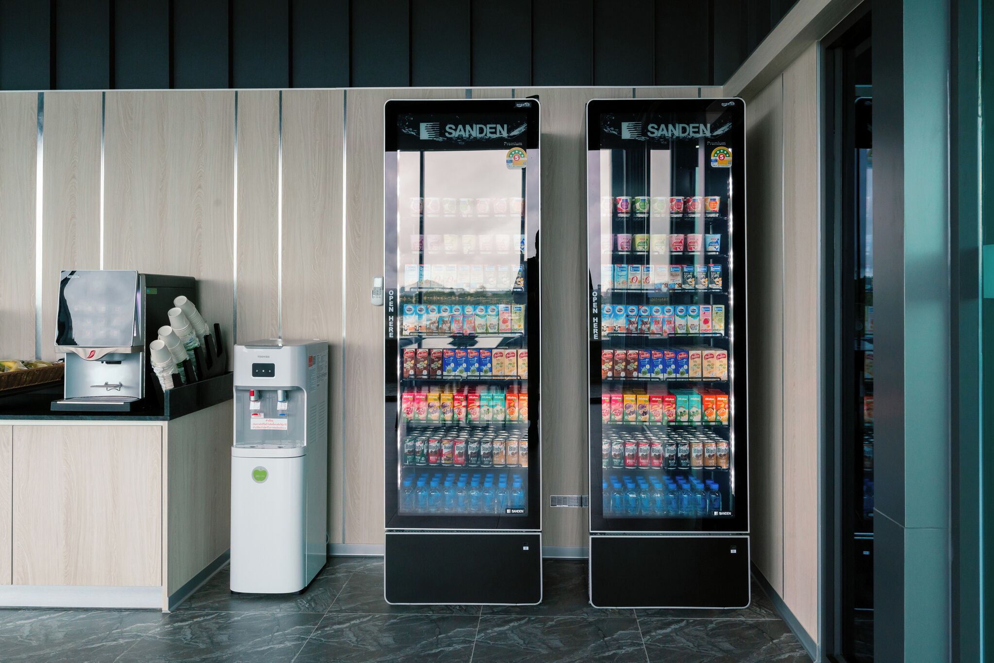 Two vending machines with a variety of beverages and snacks, a water dispenser, and a coffee machine.