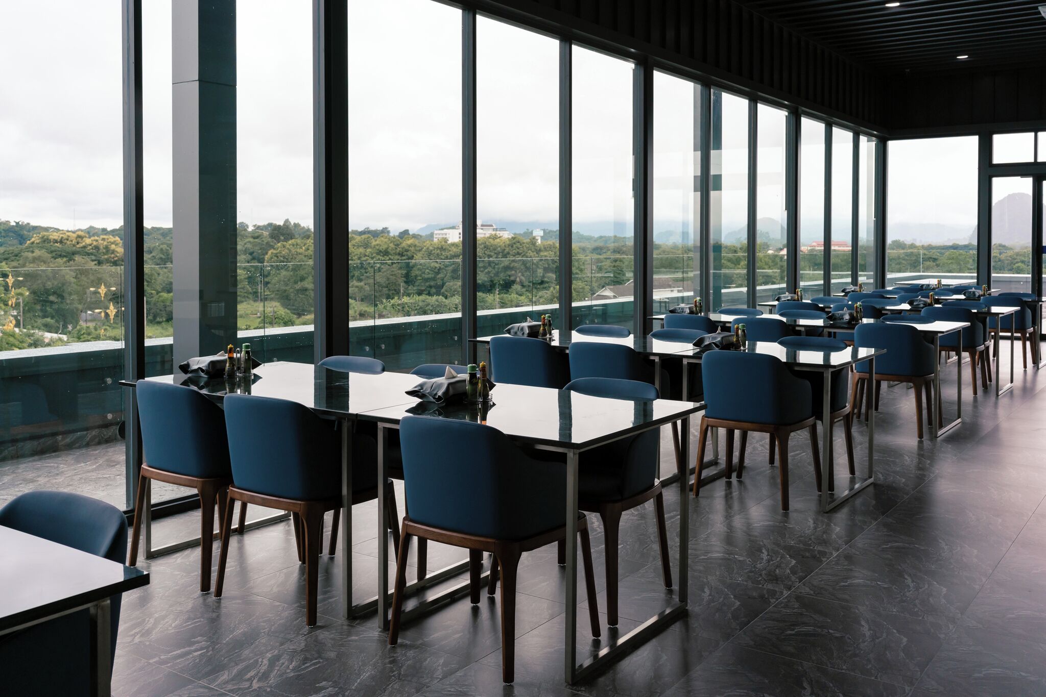 A modern dining area with large windows, tables, and chairs.