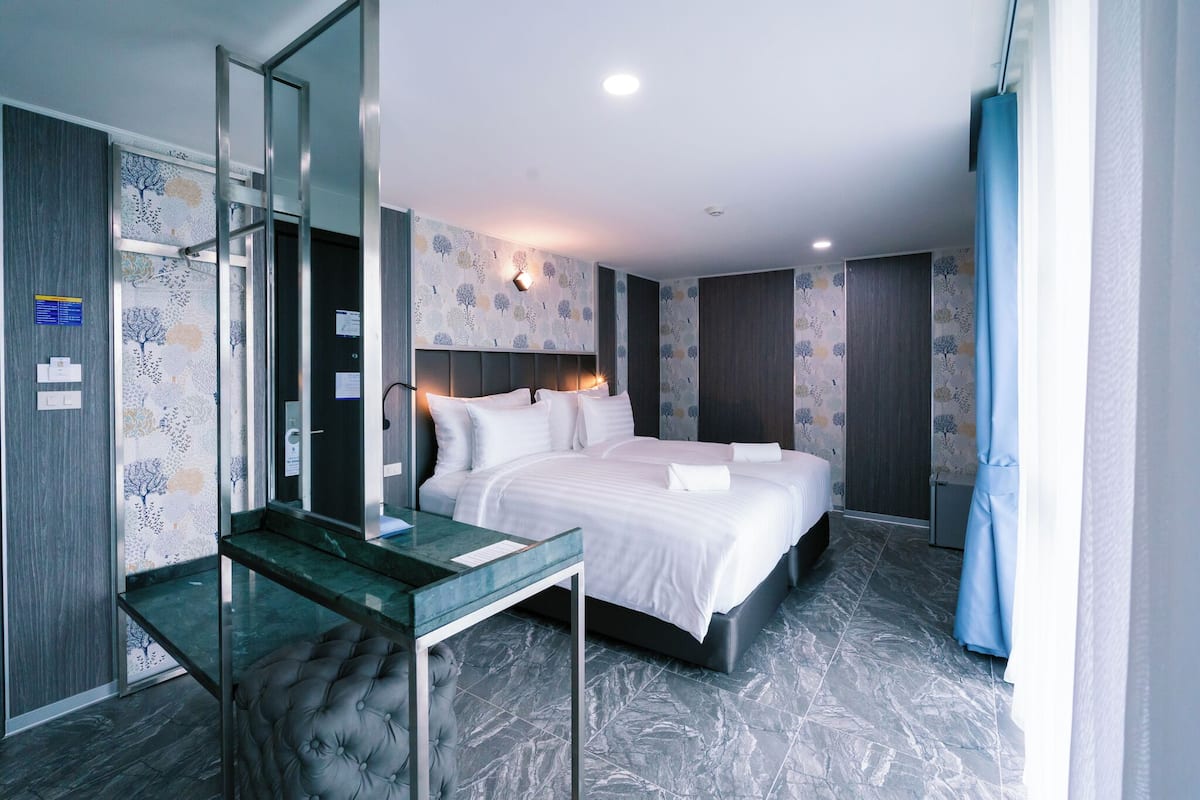 A modern hotel room with a large bed, a glass desk, and a mirror.