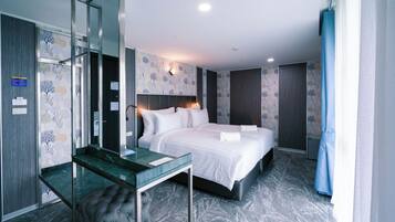 Una habitación de hotel moderna con una cama grande, un escritorio de vidrio y un espejo.