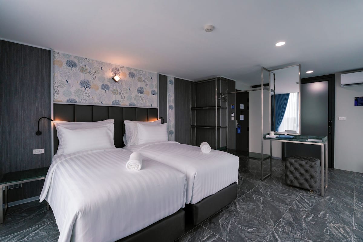 A modern hotel room with a large bed, a desk, and a mirror.
