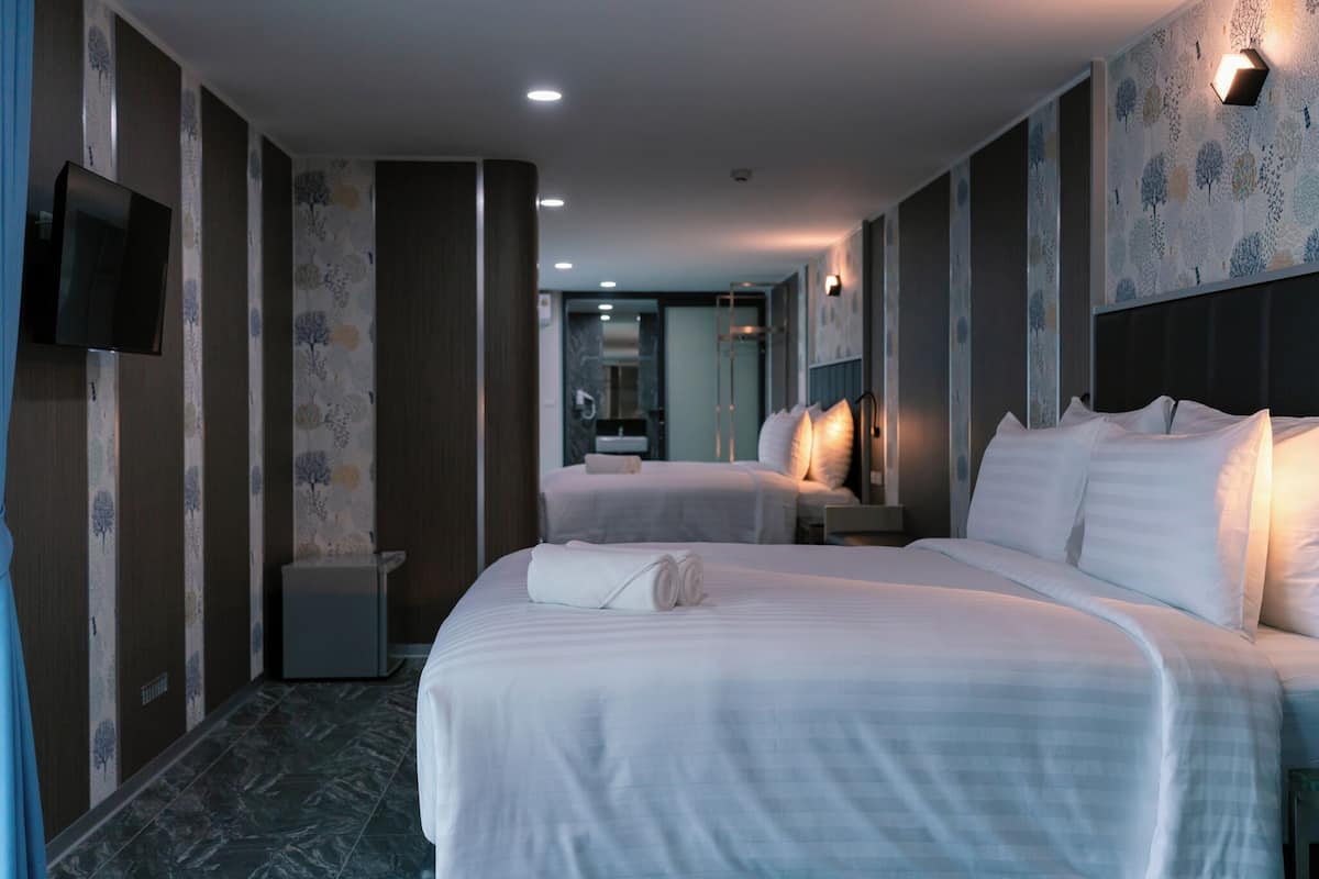 A hotel room with a large bed, a TV, and a bathroom in the background.