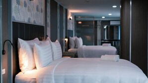 A hotel room with two beds, a bedside table, and a wall-mounted light. - One Budget Hotel Chiangrai Baanmai (Chiang Rai)