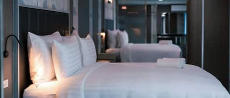 Une chambre d’hôtel avec deux lits, une table de chevet et une lampe fixée au mur.