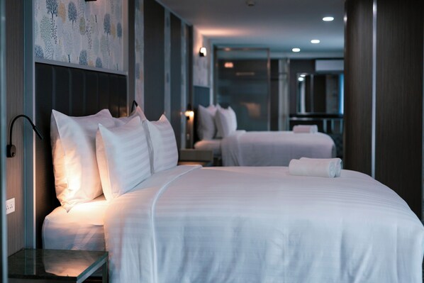 A hotel room with two beds, a bedside table, and a wall-mounted light. - One Budget Hotel Chiangrai Baanmai (Chiang Rai)