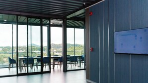 A modern conference room with large windows, a flat-screen TV, and a table with chairs. - One Budget Hotel Chiangrai Baanmai (Chiang Rai)
