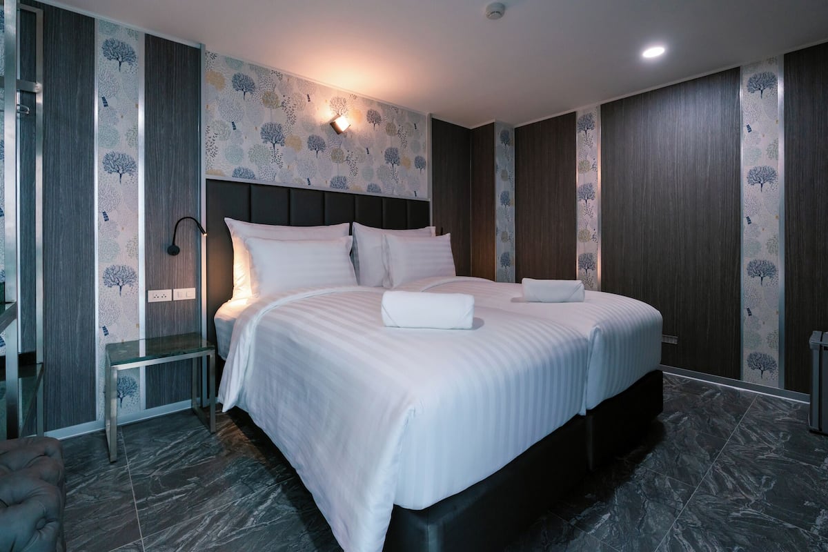 A modern hotel room with a large bed, a bedside table, and a wall-mounted light.