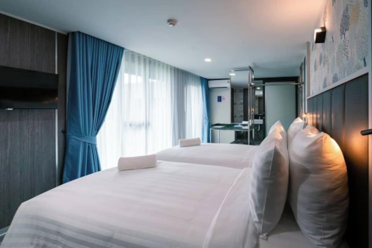 A hotel room with two beds, a desk, and a bathroom.