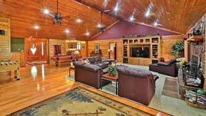 A spacious log cabin interior with a living area featuring leather sofas, a fireplace, and a television. - Family-friendly Pinetop cabin on Pinetop Country Club golf course (Pinetop Country Club)
