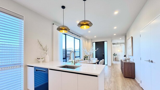 Une cuisine moderne dotée d’un îlot central, de luminaires suspendus et offrant une vue sur l’extérieur.