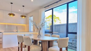 Une cuisine moderne avec des meubles blancs, un îlot central et des luminaires suspendus.