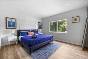Una camera da letto con un letto, comodini, una finestra e opere d'arte alle pareti.