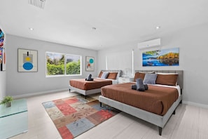 A modern bedroom with two beds, a large window, and a painting.