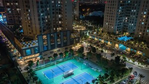 An aerial view of a residential area with a tennis court surrounded by high-rise buildings.