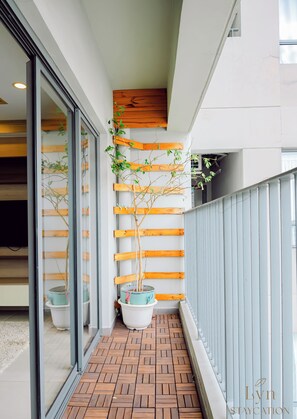 A narrow balcony with wooden flooring, potted plants, and a metal railing. - Masteri Thao Dien Apartment Complex (Ho Chi Minh City)
