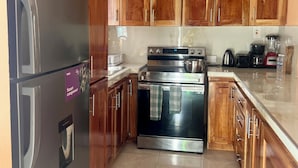 A kitchen with wooden cabinets, stainless steel appliances, and a tiled floor.