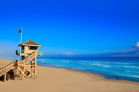 A lifeguard tower on a beach with clear blue skies and ocean waves.