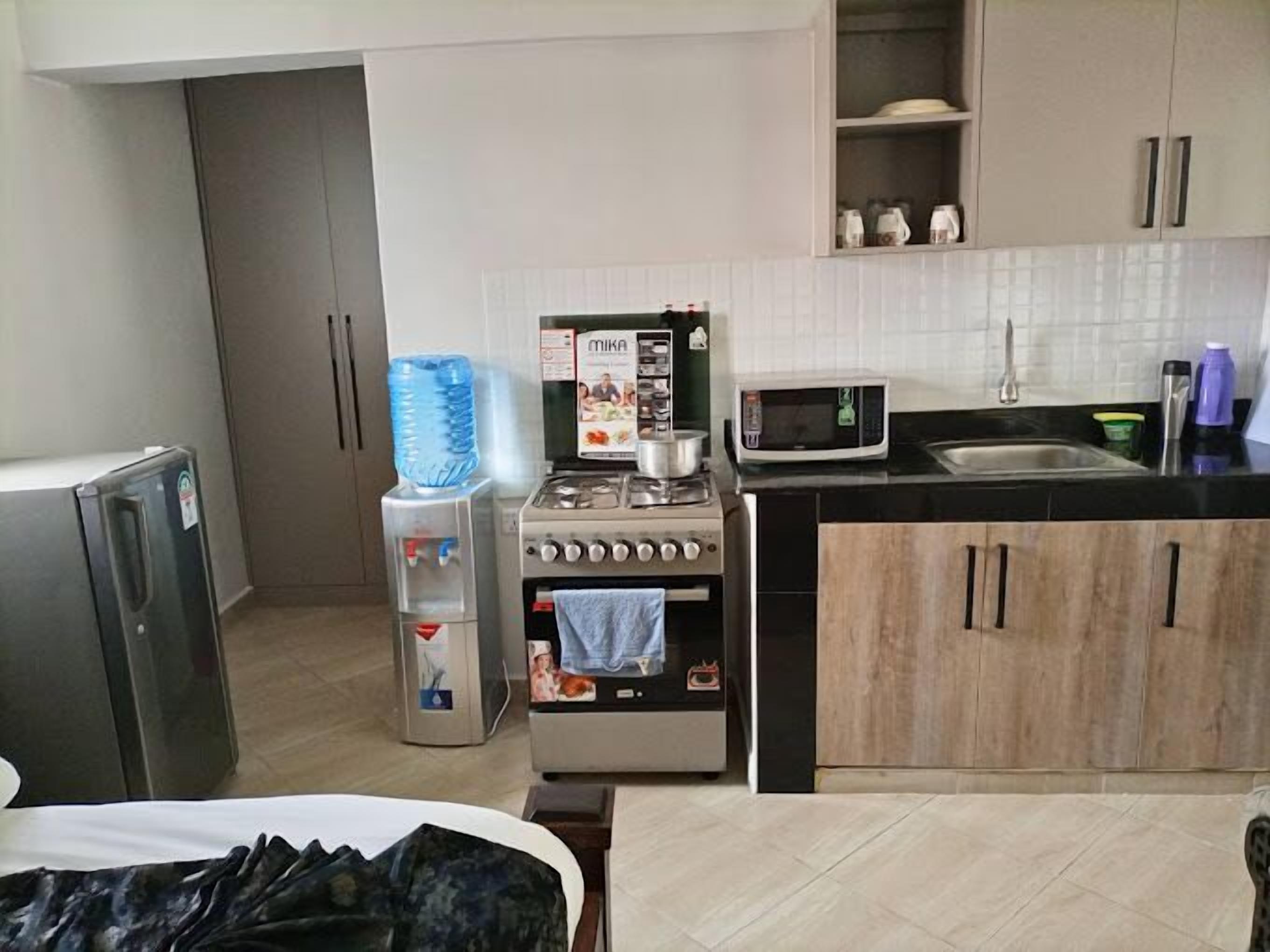 Een kleine keuken met een fornuis, magnetron en waterdispenser.