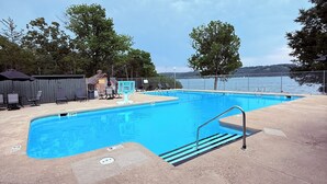 A swimming pool with a clear view of the water, a metal ladder, and a fenced area.