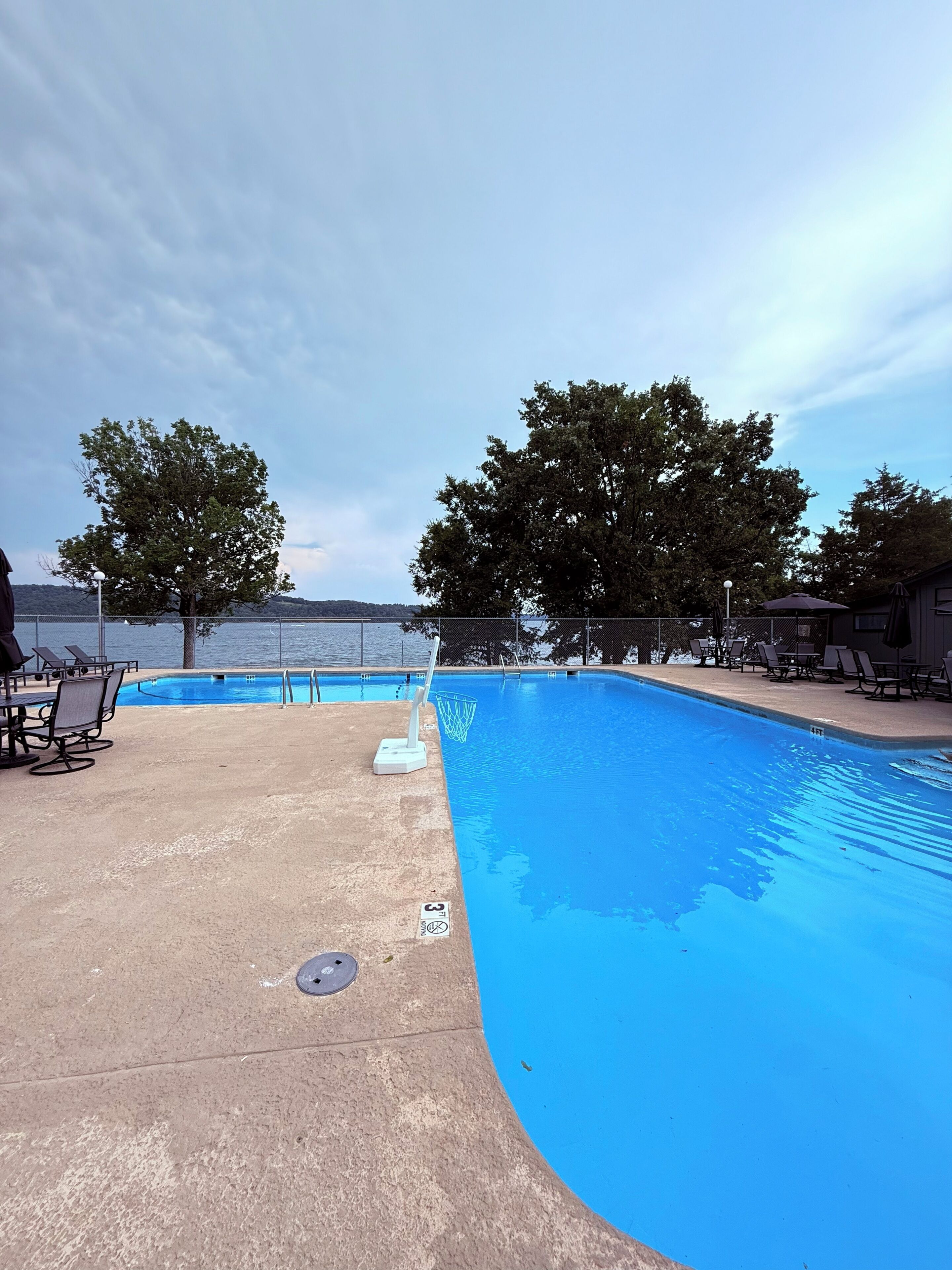 A swimming pool with lounge chairs and a view of the water.