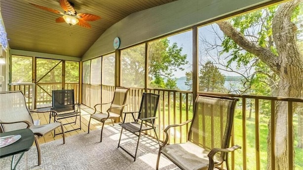 A covered outdoor seating area with chairs and a TV, overlooking a natural landscape.