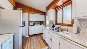 A kitchen with white cabinets, a granite countertop, and a window providing natural light.